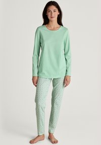 Groene longsleeve top gecombineerd met gestreepte mintgroene pyjamabroek met een geometrisch ontwerp en een zachte stoftextuur.