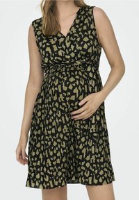 Gravidklänning i svart med ett abstrakt grönt mönster, ärmlös design, V-ringning och rynkad midja. Tillverkad av strukturerad tyg.