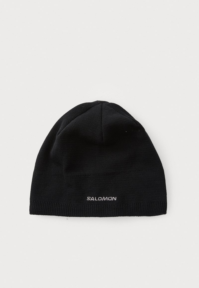 Svart stickad mössa gjord av mjukt material. Har en snug passform och en liten vit "SALOMON"-logotyp på den främre kanten.