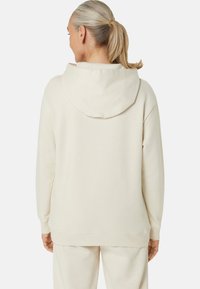 Cream-colored hoodie made of soft fabric, featuring a hood and ribbed cuffs, with a relaxed fit and no prominent patterns.
