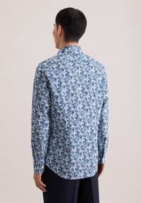Camicia a maniche lunghe blu e bianca con motivo floreale. Presenta un colletto classico e un orlo curvo. Realizzata in tessuto leggero.
