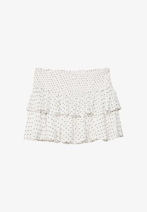 Bílá volánková sukně s černými puntíky, se smockovaným pasem a vrstveným designem, který dodává texturu a vizuální zajímavost.