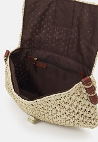 Woven straw handbag in beżowym kolorze z brązowym materiałowym wykończeniem. Posiada zasuwaną kieszeń oraz skórzane akcenty z metalowymi elementami, prezentując teksturowany wzór.