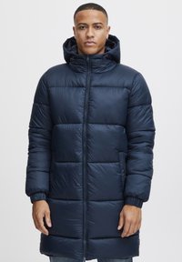 Parka blu navy con cappuccio, dotata di una chiusura frontale con zip, polsini a coste e pattern trapuntati orizzontali per isolamento e stile.