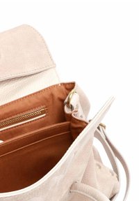 Zaino in pelle beige con una texture morbida, dotato di una fodera in tessuto marrone, una tasca con cerniera e spallacci regolabili.