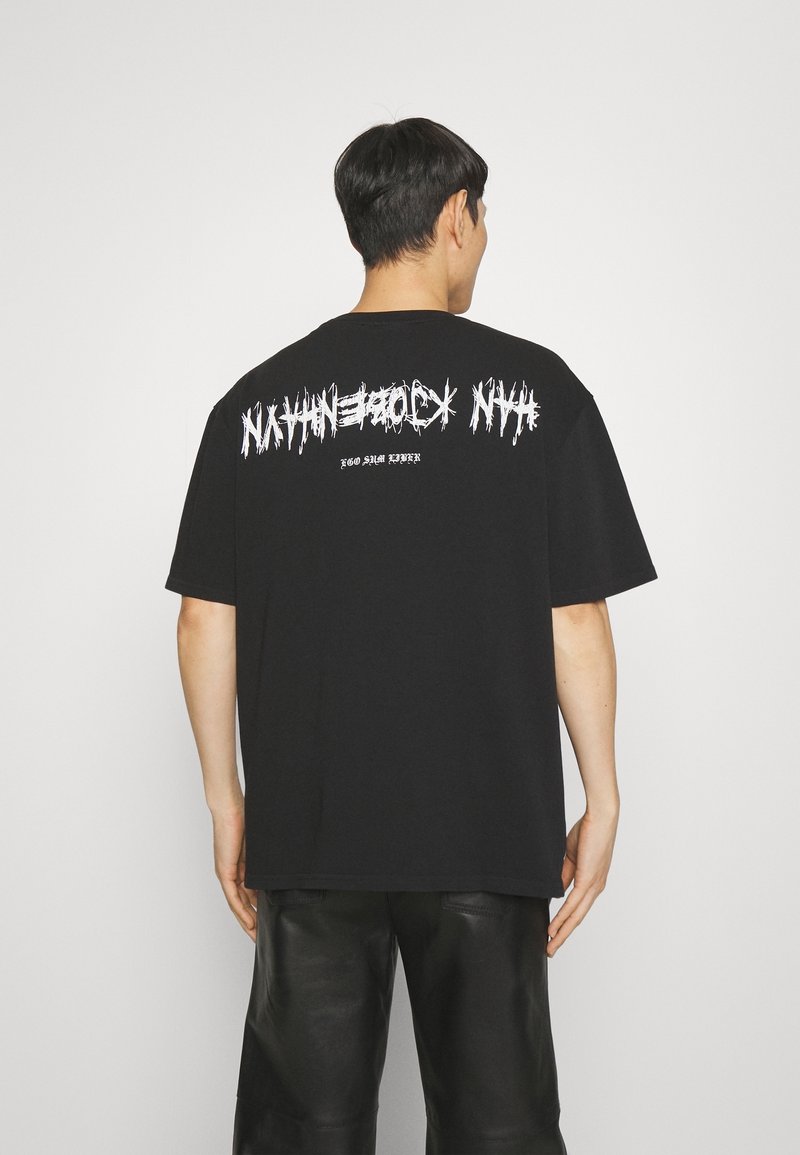 Černé bavlněné tričko s výraznými bílými grafickými nápisy na zadní straně. Volný střih s krátkými rukávy a kulatým výstřihem.