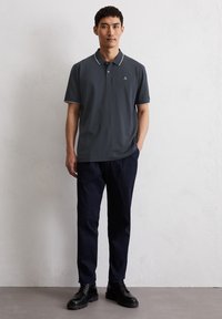 Polo shirt in dark gray with a white collar and logo, paired with navy pants and black lace-up shoes, featuring a modern fit and smooth texture.