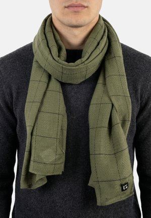 Hombre con jersey gris oscuro y bufanda verde oliva suelta con un sutil patrón de cuadros y una pequeña etiqueta con logo.