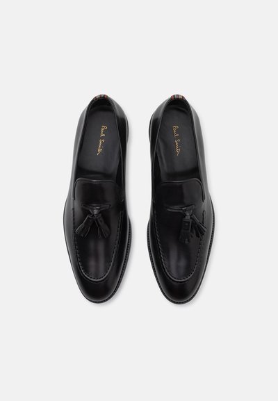 Mocassins en cuir noir avec détail à pampilles, présentant une finition lisse, un bout rond et une languette de talon rayée multicolore en contraste.