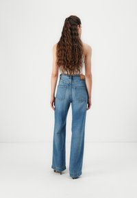Hoge taille, wijde blauwe jeans van denim, met een leren label aan de achterkant en twee achterzakken, zichtbare stiksels en een comfortabele pasvorm.