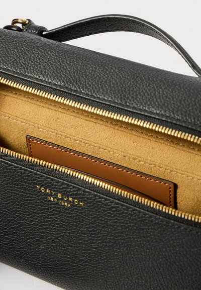 Mustan, rantalta valmistettu käsilaukku, jonka kultaiset vetoketjut ovat osittain auki, paljastaen vaaleanruskean mokkanahkaisen sisustuksen ja ruskean nahkalompakon sisällä.