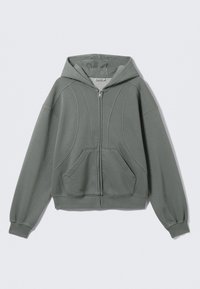 Sweat à capuche zippé gris clair en tissu doux. Il comprend une capuche, deux poches avant et des coutures courbes décoratives. Poignets et ourlet côtelés.