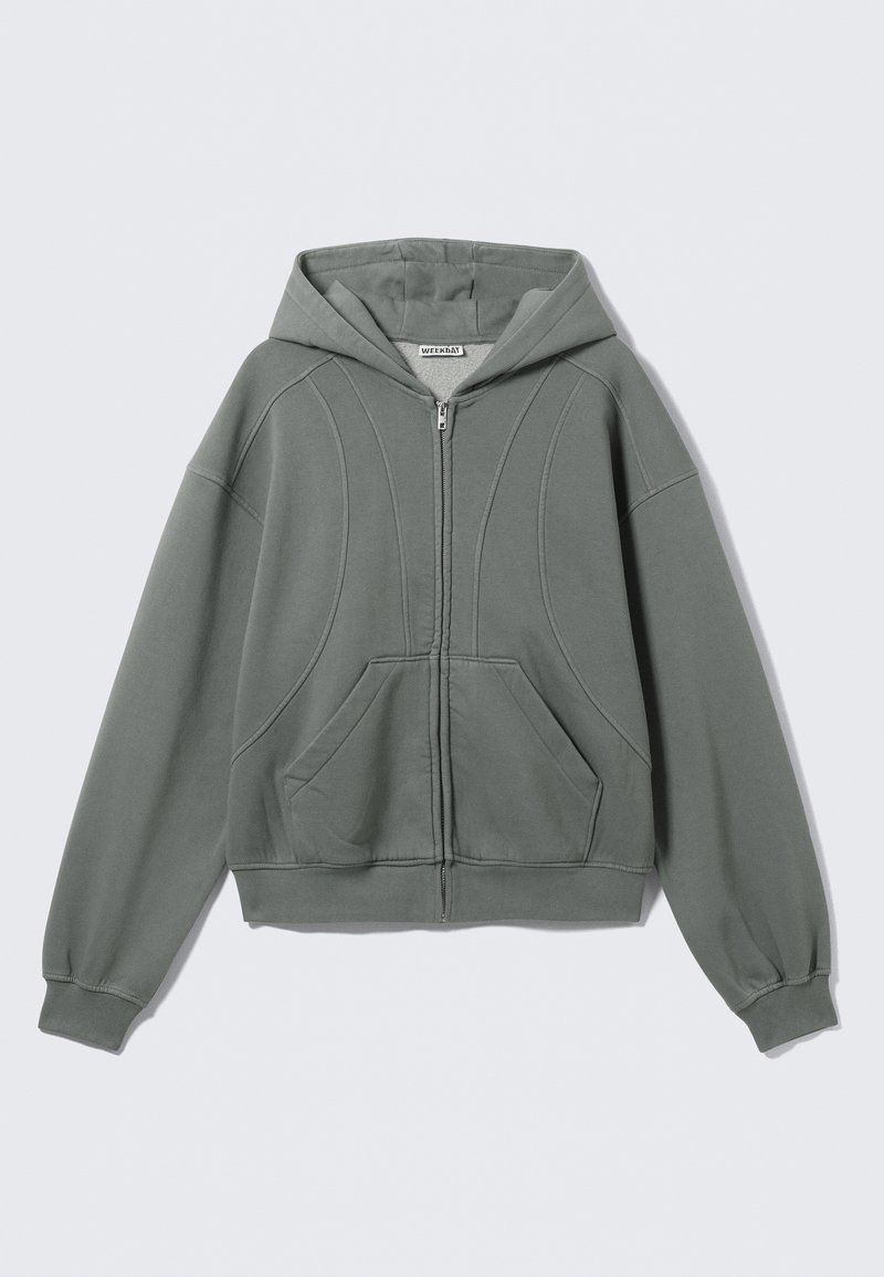 Sweat à capuche zippé gris clair en tissu doux. Il comprend une capuche, deux poches avant et des coutures courbes décoratives. Poignets et ourlet côtelés.