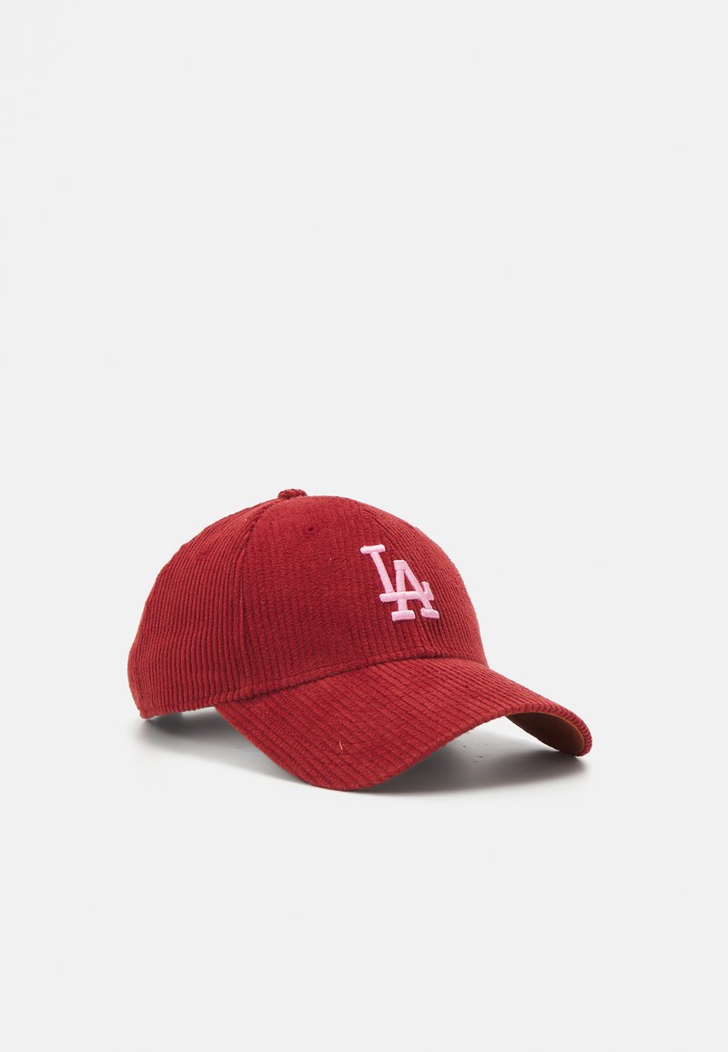 Casquette de baseball en velours côtelé rouge avec un logo "LA" rose brodé à l'avant et une visière courbée. Tissu texturé avec une forme structurée.