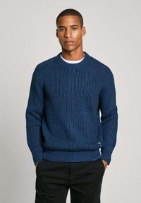 Maglione a coste di un blu navy con scollatura tonda e maniche lunghe. Presenta un tessuto текстurizzato e un piccolo etichetta sull'orlo.