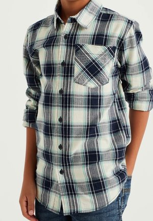 Camisa de cuadros en azul marino, verde y blanco con botones, mangas largas y un bolsillo en el pecho. Fabricada con tela texturizada y un corte relajado.