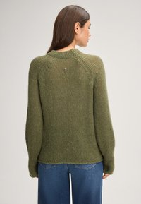 Maglione verde a maglia con maniche lunghe, scollatura rotonda e finitura testurizzata. Presenta un piccolo logo sul retro.