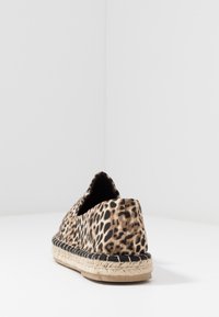 Espadrilles à motif léopard avec une tige en tissu, une semelle en jute et des coutures noires, présentant un dos arrondi et des côtés ouverts.