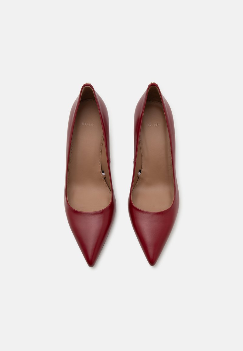 Escarpins rouges en cuir avec un bout pointu, une texture lisse et un design simple. L'intérieur présente une semelle intérieure beige clair.