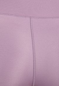 Licht paarse sportleggings van een gladde, rekbare stof met zichtbare stiksels langs de naden en een hoge tailleband.
