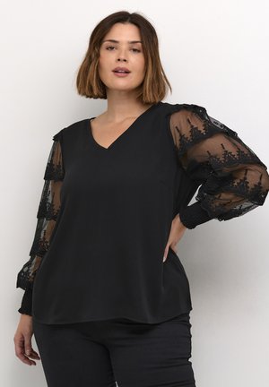 Svart blus med V-ringning, enfärgad kropp och genomskinliga spetsärmar med blommönster samt elastiska manschetter. Slät yta.