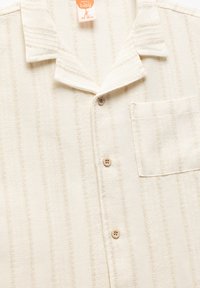 Korte mouwen, crèmekleurig shirt met verticale strepen, een kraag, een borstzak en lichtbruine knopen.