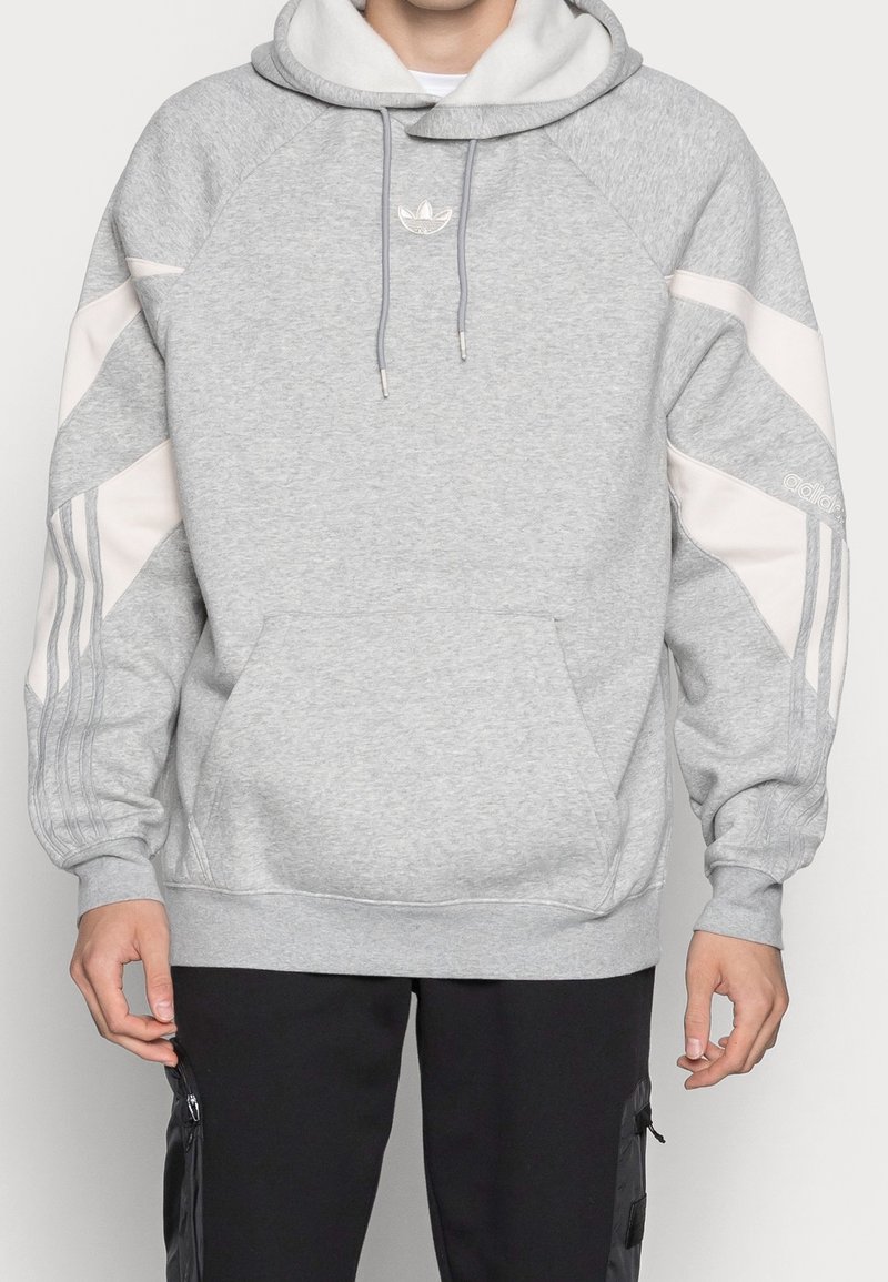 Grå sweatshirt med huva, med vita detaljer, ribbad mudd och kenguruficka. Broderad logotyp på bröstet.