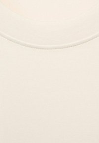 Tkanina t-shirt w kolorze kremowym z żebrowanym okrągłym dekoltem. Gładka tekstura z subtelnym, równomiernym wzorem splotu na całej powierzchni.