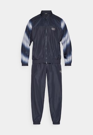 Navy tracksuit featuring a lightweight, glossy fabric. Jacket has a high collar and zip closure; pants have elastic cuffs. Subtle blue accents on sleeves.