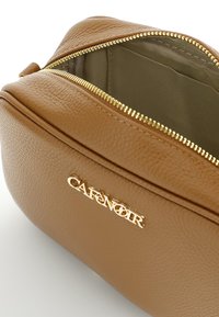 Borsa cosmetica in pelle color cuoio con zip dorata e logo. Fodera interna di colore verde oliva con scomparti. Esterno testurizzato.