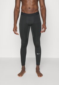 Crne Nike Pro kompresivne tajice s teksturiranim pojasom i malim bijelim Nike logom na donjoj lijevoj nozi.