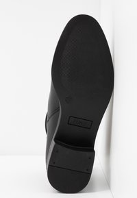 Scarpa nera con tacco, superiore in pelle liscia, punta appuntita, suola in gomma e texture sottile. Presenta il marchio "ONLY" sulla suola.
