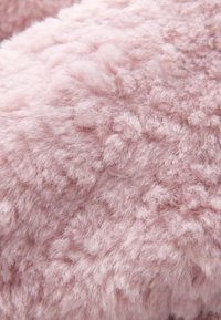 Tissu en fausse fourrure rose doux et dense avec une texture duveteuse et des fibres fines créant une surface moelleuse.