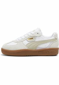 Baskets blanches en matériaux de daim et de cuir. Présentent un logo Puma beige, une semelle en caoutchouc texturée et des lacets blancs. Design basse.