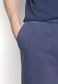 Námořnická tričko z bavlněné směsi s kulatým výstřihem, krátkými rukávy a uvolněným střihem, spárované s odpovídajícími námořnickými tepláky s bočními kapsami.