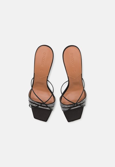 Black heeled sandals featuring a square toe, slender cross straps, and a shimmering rhinestone accent along the vamp on a nude footbed.