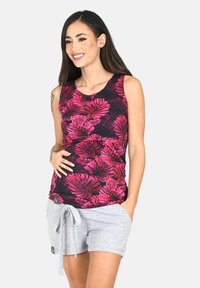 Top senza maniche con un vivace motivo di foglie tropicali rosa e viola su uno sfondo scuro, abbinato a pantaloni corti grigi chiari con coulisse.