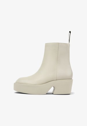 Botas de tobillo beige hechas de cuero suave, con una suela de plataforma gruesa y un tacón texturizado. Incluye una pestaña de agarre en la parte trasera.