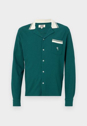 Tyrkis langermet skjorte med krage, hvite striper og en brystlomme med et lite hjerte-design. Teksturert stoff og knappelukking.