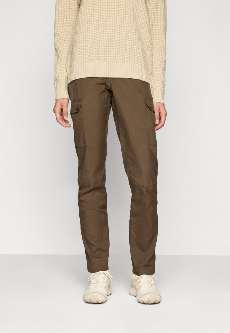 Lower body of person wearing brown cargo pants, cream knit sweater, and cream sneakers against plain light background.