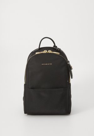 Petit sac à dos noir Michael Kors avec fermetures éclair dorées, une poche avant et une poignée supérieure sur fond blanc.