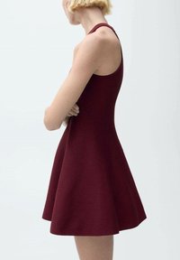 Bordo haljina bez rukava s prilagođenim korzetom i lepršavom suknjom, izrađena od teksturirane tkanine, koja se ističe čistim, minimalističkim dizajnom.