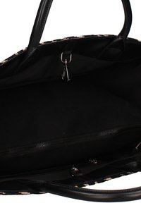 Intérieur de sac à main noir avec doublure en tissu, poche zippée, fermoir en métal et poignées doubles visibles.