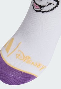 Biela ponožka s fialovou špičkou, žltý text "Disney" a čiastočne vyšívaná usmievajúca sa kartónová tvár blízko členku.