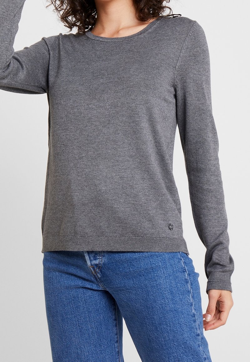 Maglione grigio a maniche lunghe realizzato in tessuto a maglia liscia, con scollatura a girocollo e orlo a coste. Dettaglio del logo ben visibile sul lato sinistro in basso.