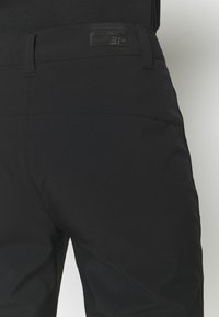 Black pants with a smooth, stretchy fabric. Features a clean waistband and subtle stitching details. Includes a small branded label on the back.