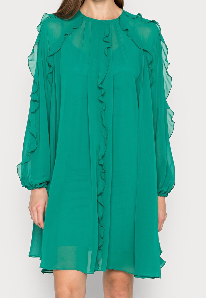 Zelené šifonové šaty s dlouhými, nabíranými rukávy, které mají volánkový výstřih a přední zapínání. Hladká, lehká tkanina s volným střihem.