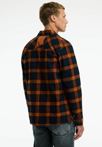 Geruite flanellen overhemd in marineblauw en oranje, met een spreidkraag, lange mouwen en knoopmanchetten. Zachte textuur met een ontspannen pasvorm.