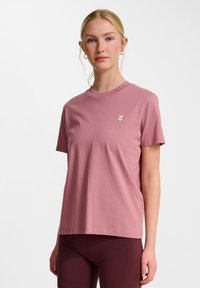 Kortærmet T-shirt med rund hals i lys pink bomuld. Har et lille tre-chevrons logo i nedtonede farver på brystet.