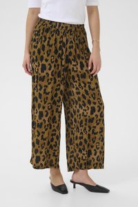 Pantalons marron à jambes larges avec un imprimé léopard noir, dotés d'une taille élastique. Associés à des chaussures noires à bout pointu.